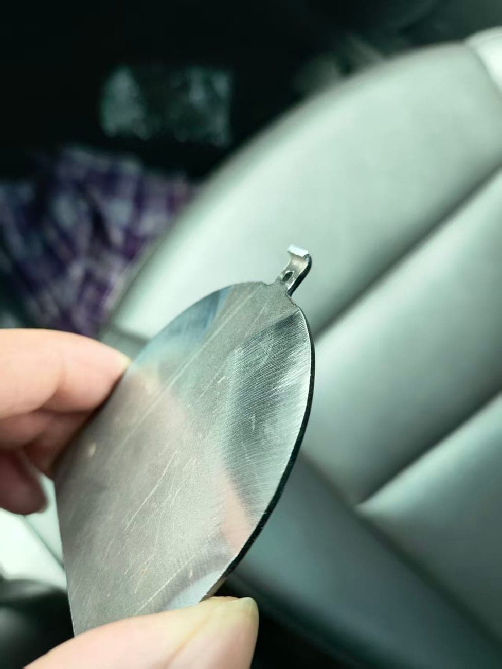 Small flat metal part with a rounded profile and a narrow mounting tab