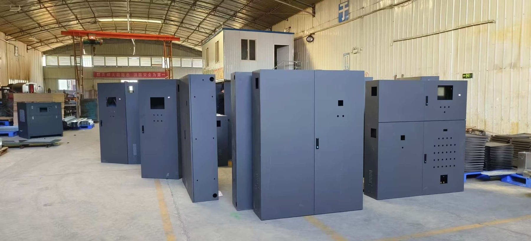 Custom gray machine cabinets with access doors, display openings and ventilation holes in the workshop