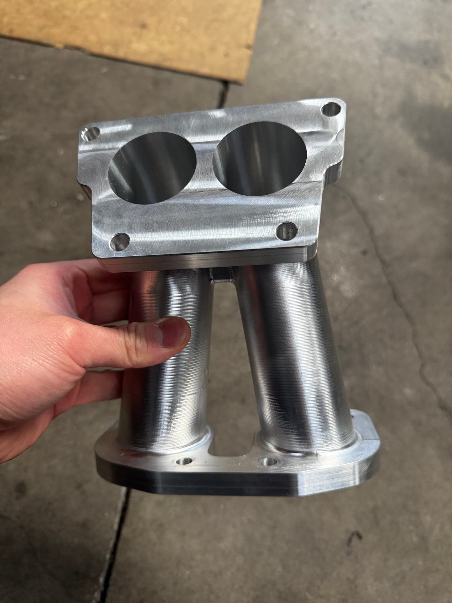 Front view of a twin-cylinder machined part with two circular bores and flange mounting holes