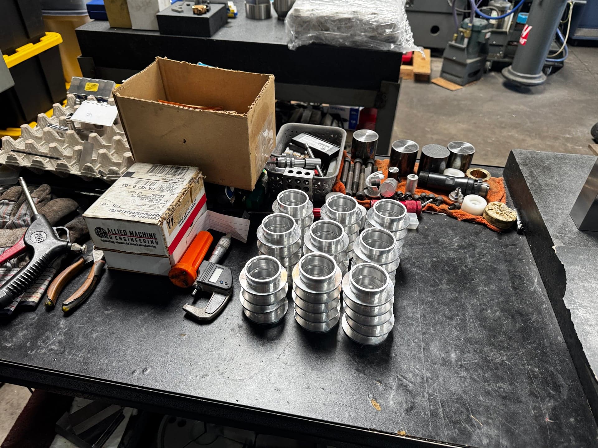 Rows of stacked stepped ring-shaped machined parts on a workshop bench